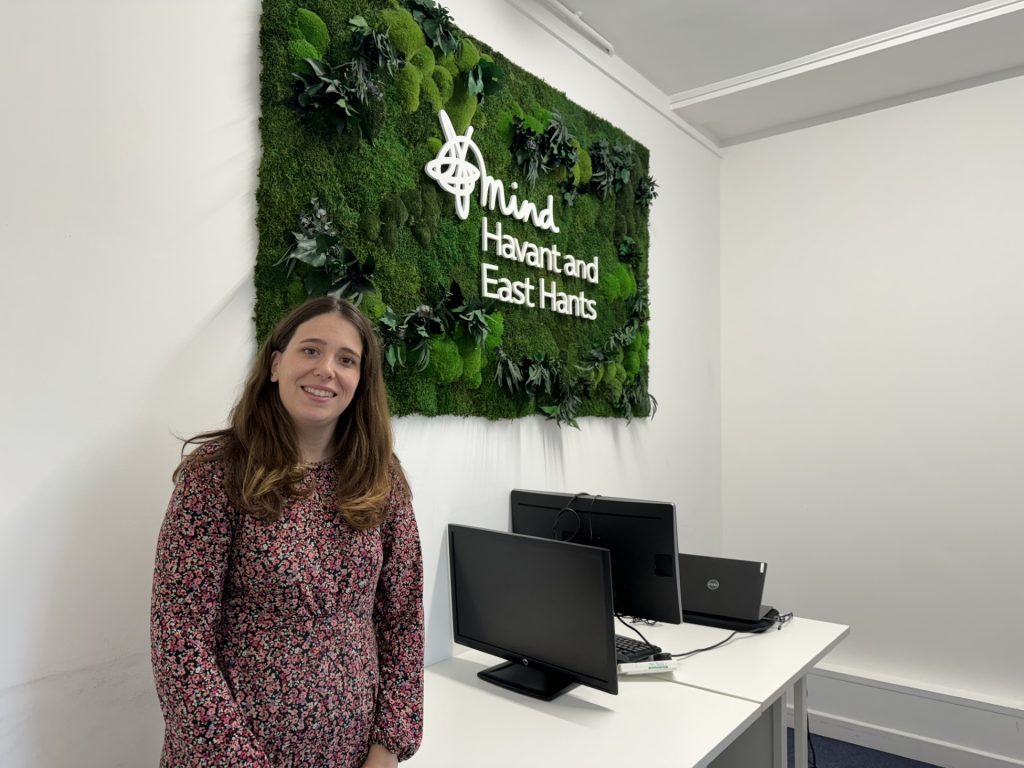 Jenny stood in front of plant wall with HEH Mind logo in white text